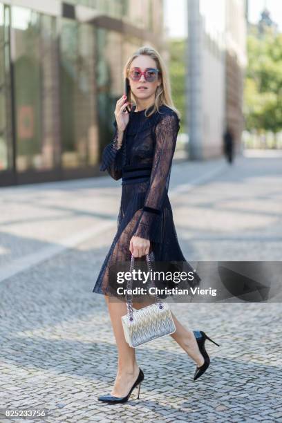 Sonia Lyson wearing a navy sheer cocktail party dress with long sleeves from Tara Jarmon, a silver Miu Miu bag, MCM sunglasses, black Gianvito Rossi...