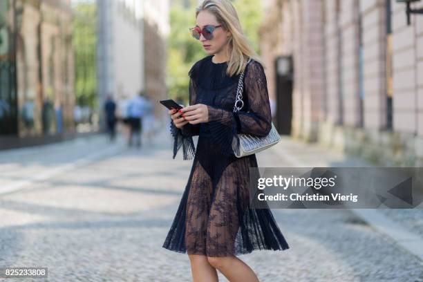 Sonia Lyson wearing a navy sheer cocktail party dress with long sleeves from Tara Jarmon, a silver Miu Miu bag, MCM sunglasses, black Gianvito Rossi...