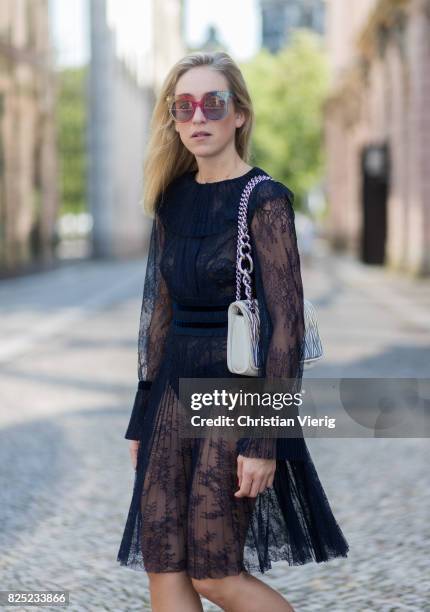 Sonia Lyson wearing a navy sheer cocktail party dress with long sleeves from Tara Jarmon, a silver Miu Miu bag, MCM sunglasses, black Gianvito Rossi...