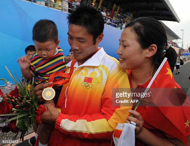 China's Meng Guanling holds his son Meng Yu Huang while his wife Xu Feng Yue looks on following the medals ceremony after winning the men's canoe...
