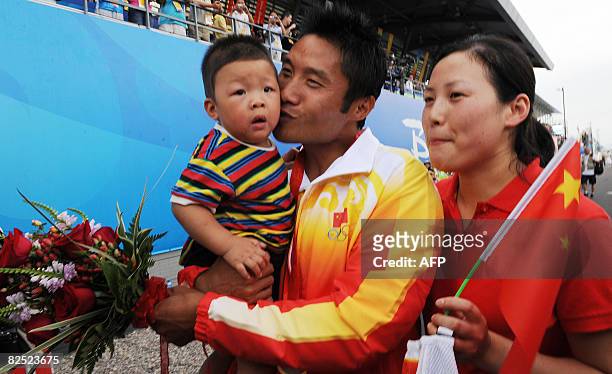 China's Meng Guanling holds his son Meng Yu Huang while his wife Xu Feng Yue looks on following the medals ceremony after winning the men's canoe...