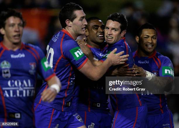 Chris Housten and Danny Buderus congratulate Wes Naiqama of the Knights after he scored a try during the round 24 NRL match between the Newcastle...