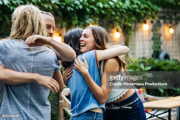 a group of friends embrace, excited to see each other at barbecue meetup - freundschaft stock-fotos und bilder