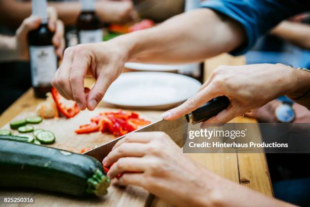 couple preparing food together at barbecue with friends - mergpompoen stockfoto's en -beelden