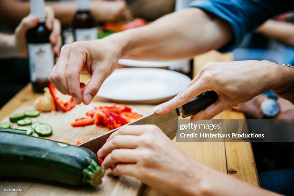 Couple Preparing Food Together At Barbecue With Friends