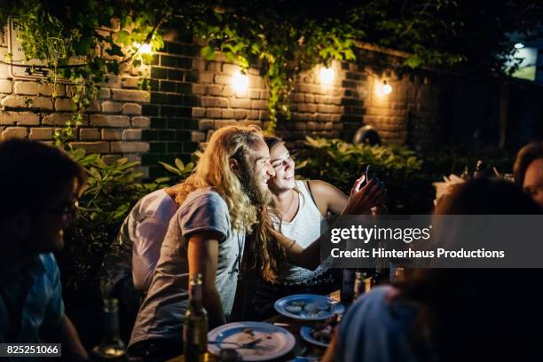 a young couple are looking over photos together on a smartphone - smartphone cuisine stock-fotos und bilder