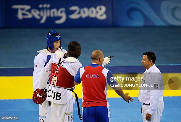 Angel Valodia Matos of Cuba points at referee Chakir Chelbat of Sweden while Matos' coach discusses with the referee and Arman Chilmanov of...