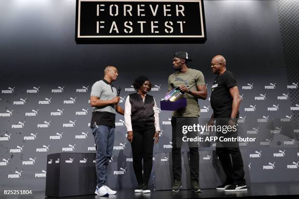 Jamaica's Usain Bolt holds his race spikes as he poses with his mother Jennifer, , father Wellesley and host, Welsh former athlete Colin Jackson...