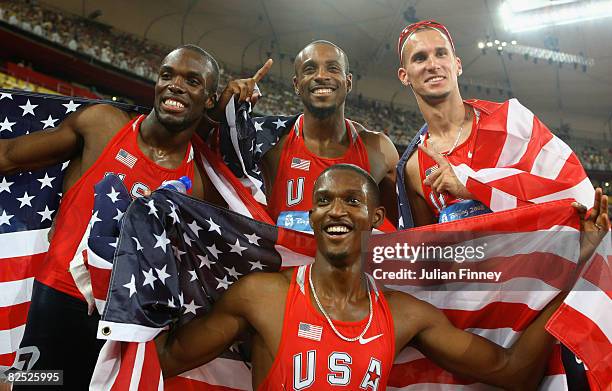 LaShawn Merritt, Angelo Taylor, Jeremy Wariner and David Neville of the United States pose draped in their countries flag after winning the gold...