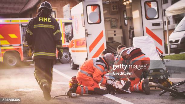 sanitäter helfen verletzten radfahrer - injured street stock-fotos und bilder