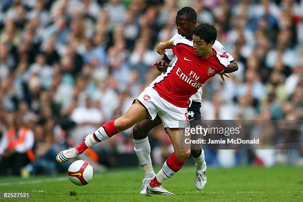 Samir Nasri of Arsenal battles for the ball with John Pantsil of Fulham during the Barclays Premier League match between Fulham and Arsenal at Craven...