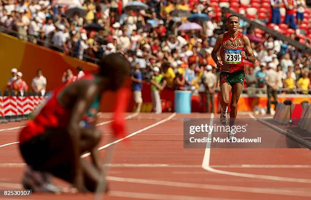 Sammy Wanjiru of Kenya kneels on the track as Jaouad Gharib of Morocco finishes in second place after winning the Men's Marathon held at the National...