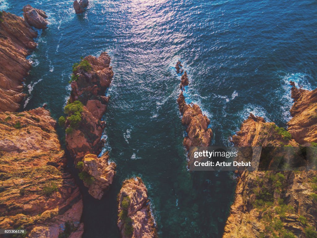 Aerial picture taken with drone flying over the stunning Costa Brava in the Mediterranean Sea with beach hidden between rocky terrain and stunning landscape.