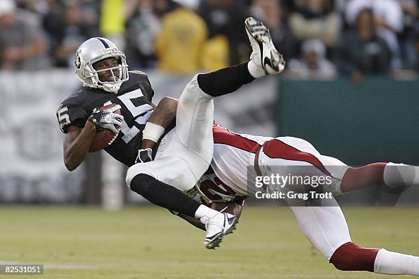 Wide receiver Johnnie Lee Higgins of the Oakland Raiders is tackled by defensive back Adrian Wilson of the Arizons Cardinals during a preseason game...