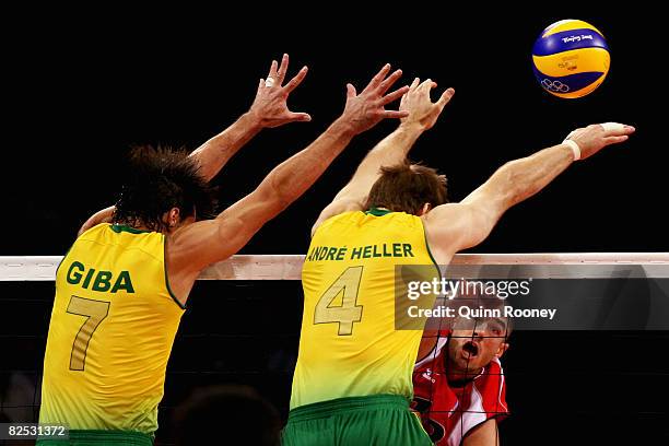 Clayton Stanley of the United States smashes as Gilberto Godoy Filho and Andre Heller of Brazil block in the Gold Medal volleyball match between the...