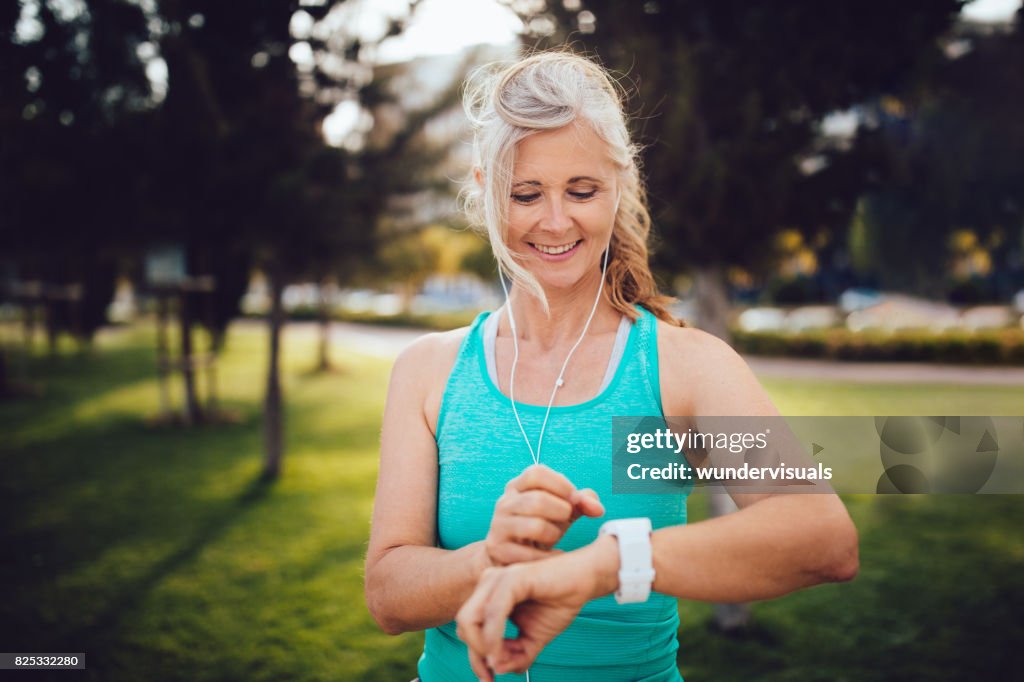 Athletic mature woman monitoring her running performance on smartwatch
