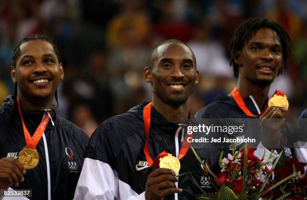 Carmelo Anthony, Kobe Bryant and Chris Bosh of the United States stand on the podium during the national anthem after defeating Spain in the gold...