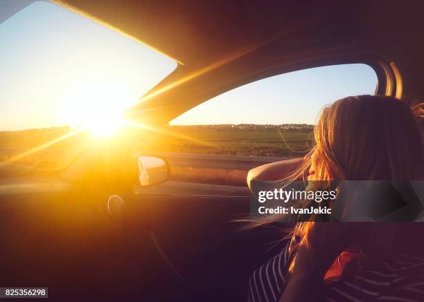joven disfrutando el paseo en coche al atardecer - car road sunset fotografías e imágenes de stock