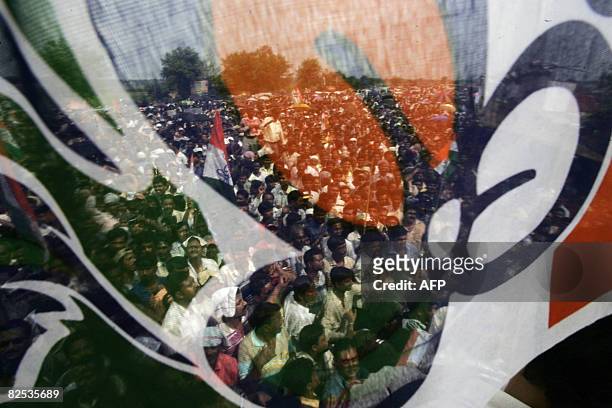 Trinamool Congress supporters are seen through a party flag as they take part in a rally during an indefinite agitation in front of the main entrance...