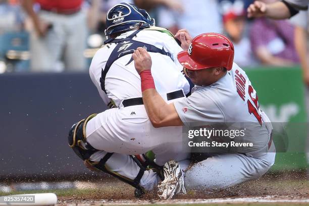 Kolten Wong of the St. Louis Cardinals is tagged out at home plate by Manny Pina of the Milwaukee Brewers during the third inning of a game at Miller...