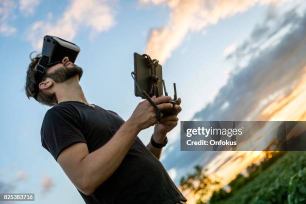 man flying a drone with virtual reality goggles headset - flying goggles imagens e fotografias de stock