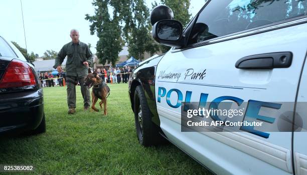 Dog is lead to a police vehicel during a display by the Monterey Park police department at a "Night Out" activity on August 1, 2017 in Monterey Park,...