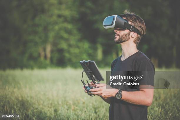 man flying a drone with virtual reality goggles headset - flying goggles imagens e fotografias de stock