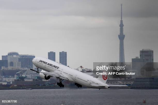 The landmark Tokyo Skytree tower is seen with the city skyline as a Japan Airlines Boeing 777 takes off at Haneda international airport in Tokyo on...