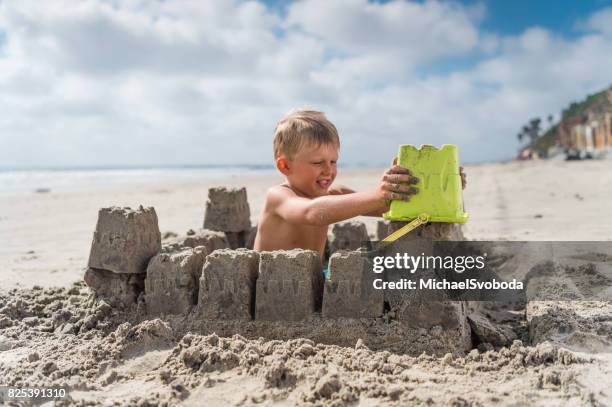 blonde junge am strand eine sandburg bauen - sandburg stock-fotos und bilder