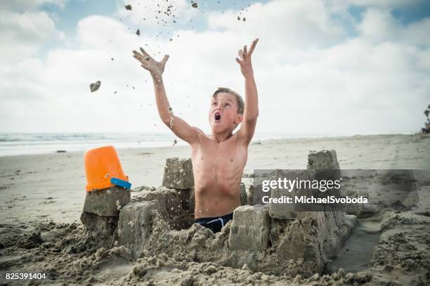 blonde boy at the beach building a sand castle - throwing stock pictures, royalty-free photos & images