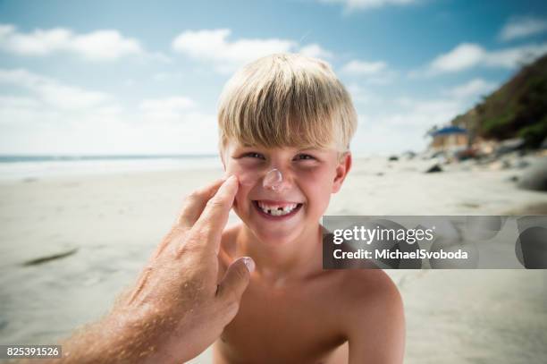 papa, die anwendung von sonnencreme auf seine jungen am strand - subjektive kamera ungewöhnliche ansicht stock-fotos und bilder