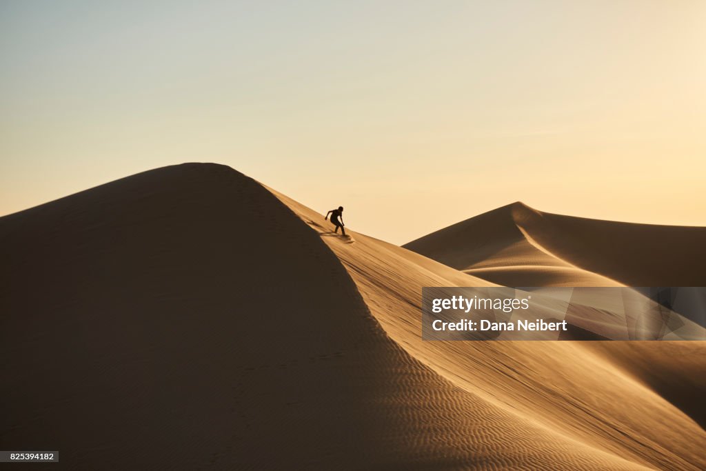 Boy sand surfing in the desert sand dunes