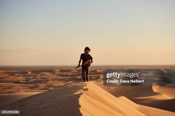 boy sand surfing in the desert sand dunes - sand boarding stock pictures, royalty-free photos & images