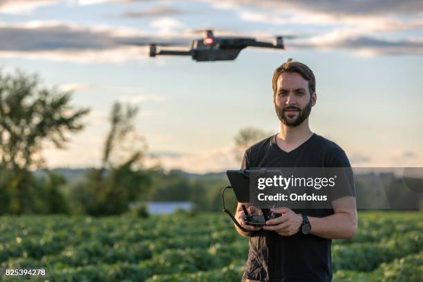 man pilot using drone remote controller at sunset - quadcopter stock pictures, royalty-free photos & images