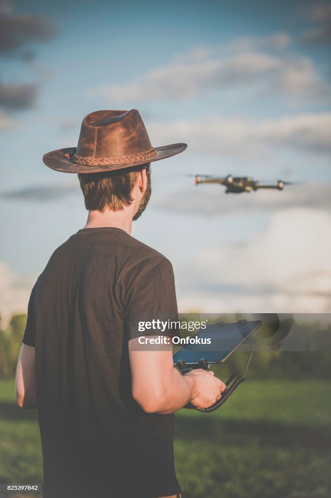 Man Landwirt-Pilot mit Drone Fernbedienung bei Sonnenuntergang