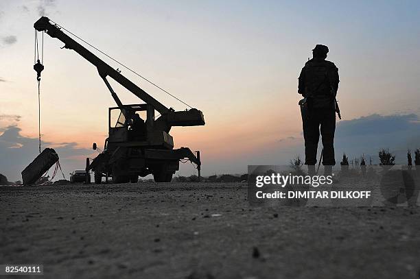 Russian peacekeeper looks at a crane removing the last checkpoint on the Gori-Tbilisi road on August 22 near the village of Khurvaleti. Hundreds of...