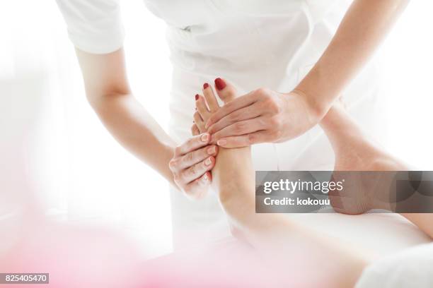 le dita dell'estetista massaggiano delicatamente i piedi di una donna giovane e bella. - pedicure foto e immagini stock