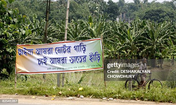 An Indian villager walks past a Trinamool Congress slogan written in Bengali which says "We don't need motor car, but rice cooking pot" displayed...