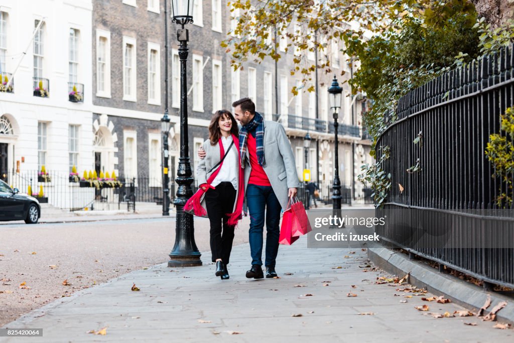 Smiling couple walking along the street with shopping bags