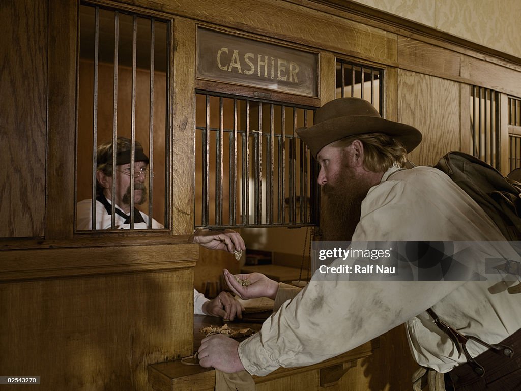 Gold miner selling gold to teller at bank