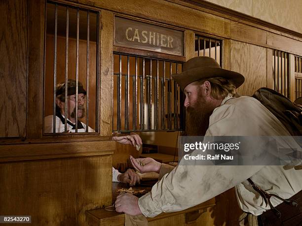 gold miner selling gold to teller at bank - teller stock pictures, royalty-free photos & images