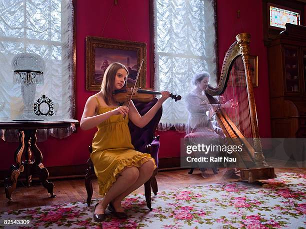 girl playing violin with ghost presence in room - ghost player stock pictures, royalty-free photos & images