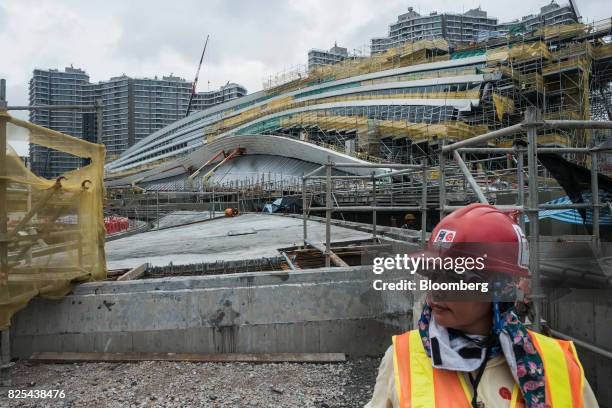 Worker looks on as the West Kowloon Terminus of the Guangzhou-Shenzhen-Hong Kong Express Rail Link , developed by MTR Corp., stands under...