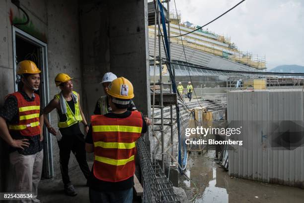 Workers look on as the West Kowloon Terminus of the Guangzhou-Shenzhen-Hong Kong Express Rail Link , developed by MTR Corp., stands under...