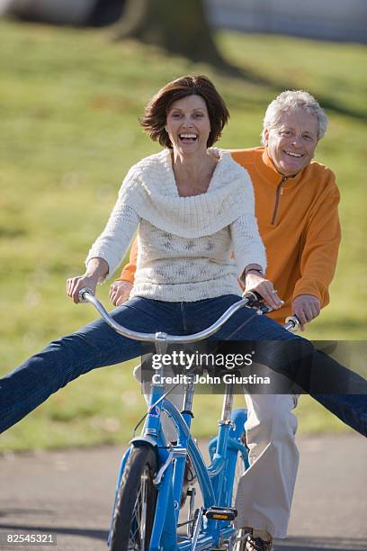 mature couple (50-60) riding tandem bike - tandem stockfoto's en -beelden