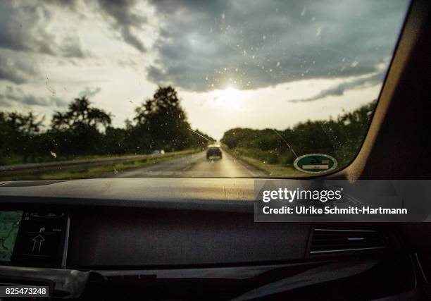 view through front window of car while driving on road at sunset - auto innenansicht stock-fotos und bilder