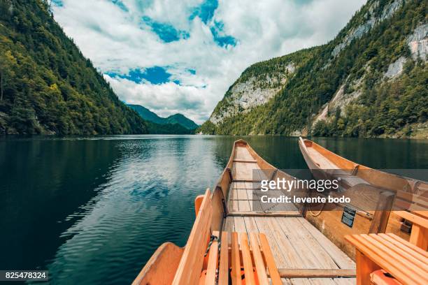 wooden boat on a lake reflection with mountains and clouds and blue sky. tranquil nature landscape for inspirational ideas - österreich durchblick stock-fotos und bilder