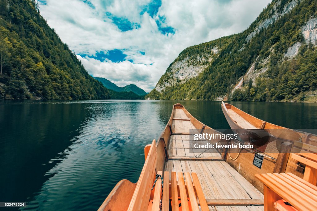 Wooden boat on a lake reflection with mountains and clouds and blue sky. Tranquil nature landscape for inspirational ideas