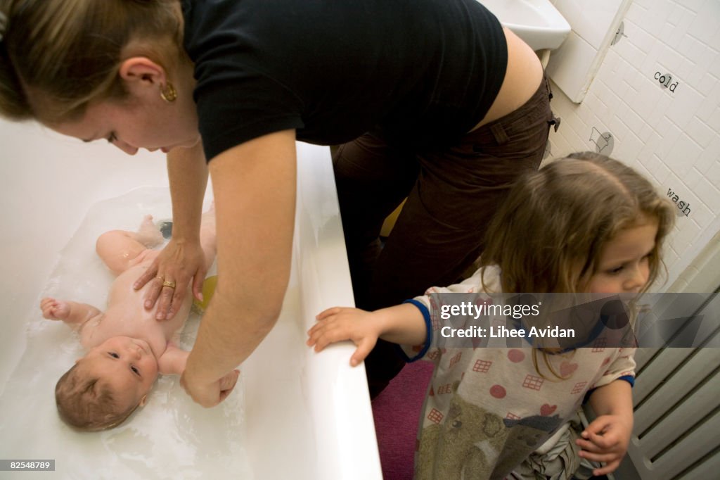 Mother and daughter bathe baby