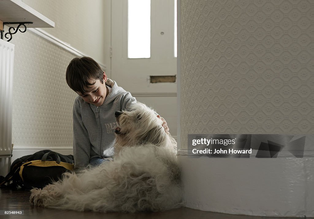 Boy stroking dog in hallway